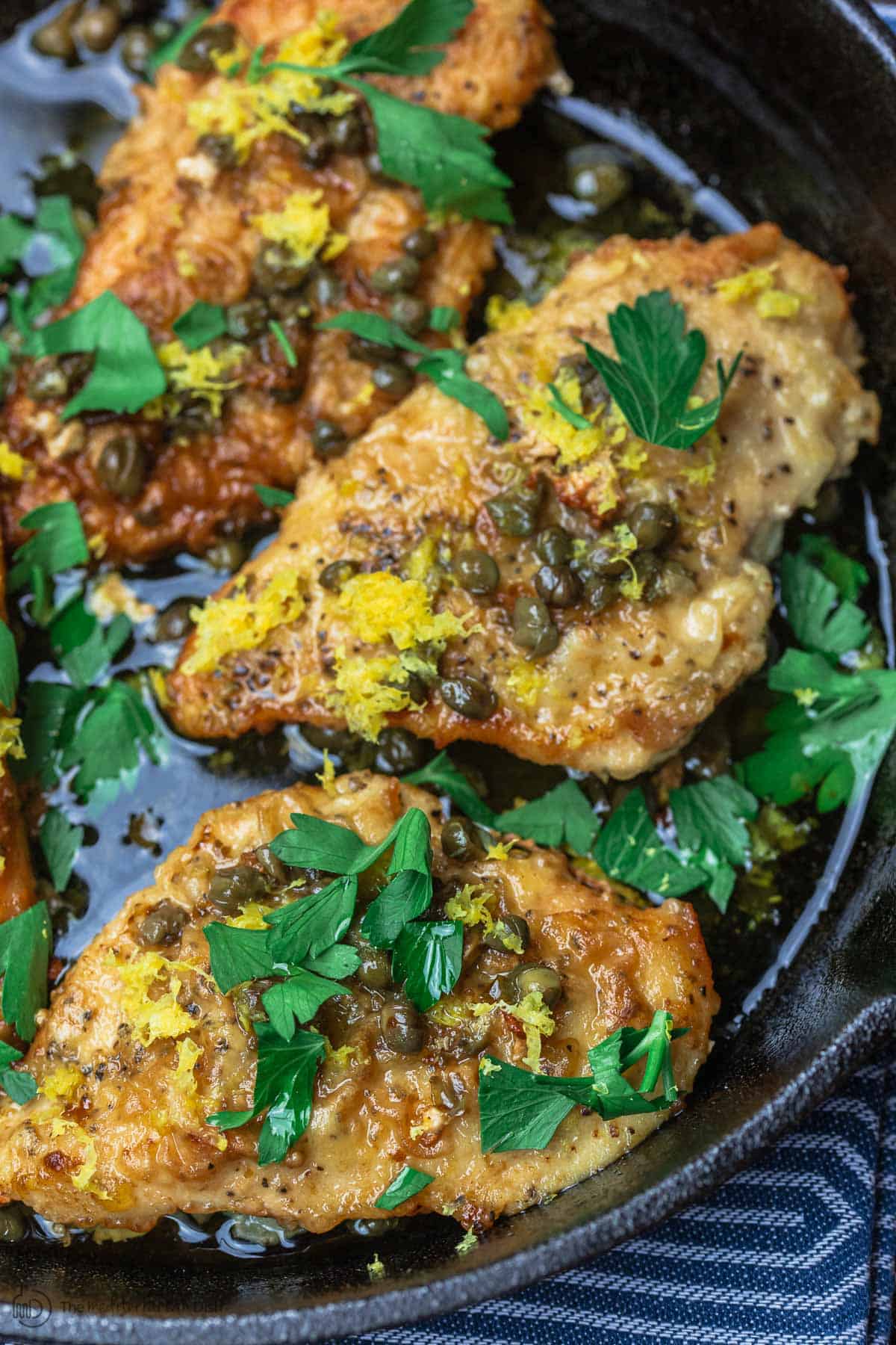 3 pieces of chicken piccata topped with a garnish of parsley