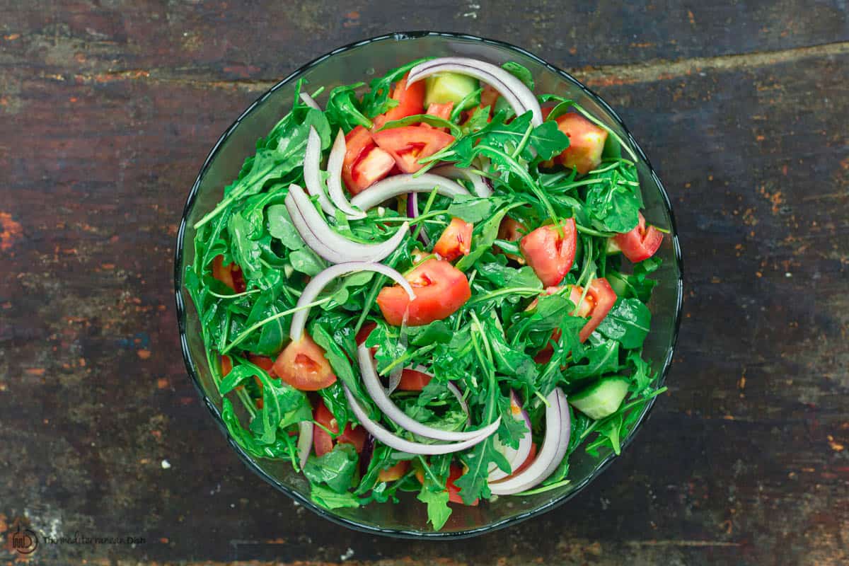 Arugula salad with tomatoes, cucumbers, and onions