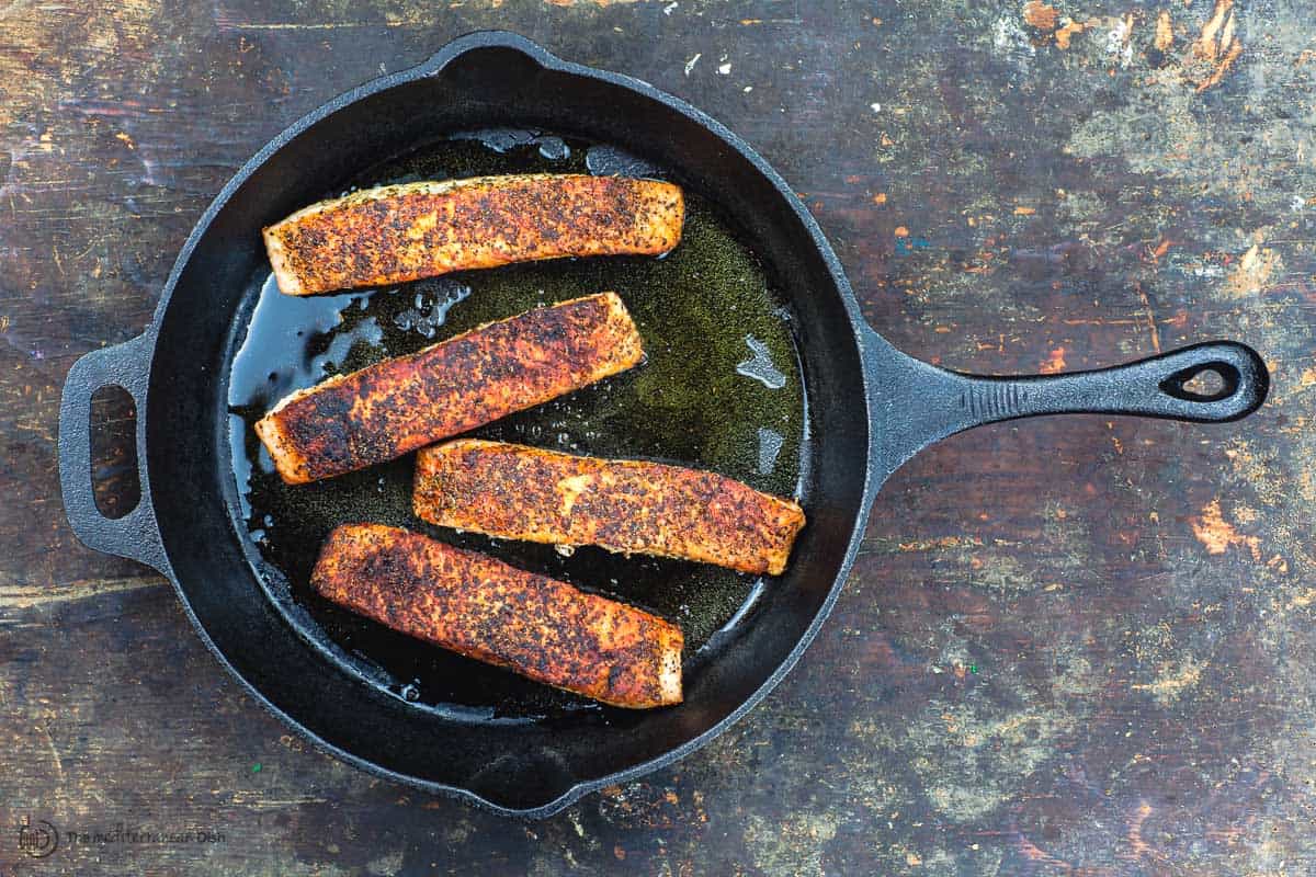 Salmón frito con aceite de oliva en sartén de hierro fundido