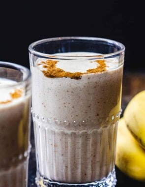 Tahini Date Banana Shake in glass. Bananas on the side