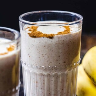 Tahini Date Banana Shake in glass. Bananas on the side