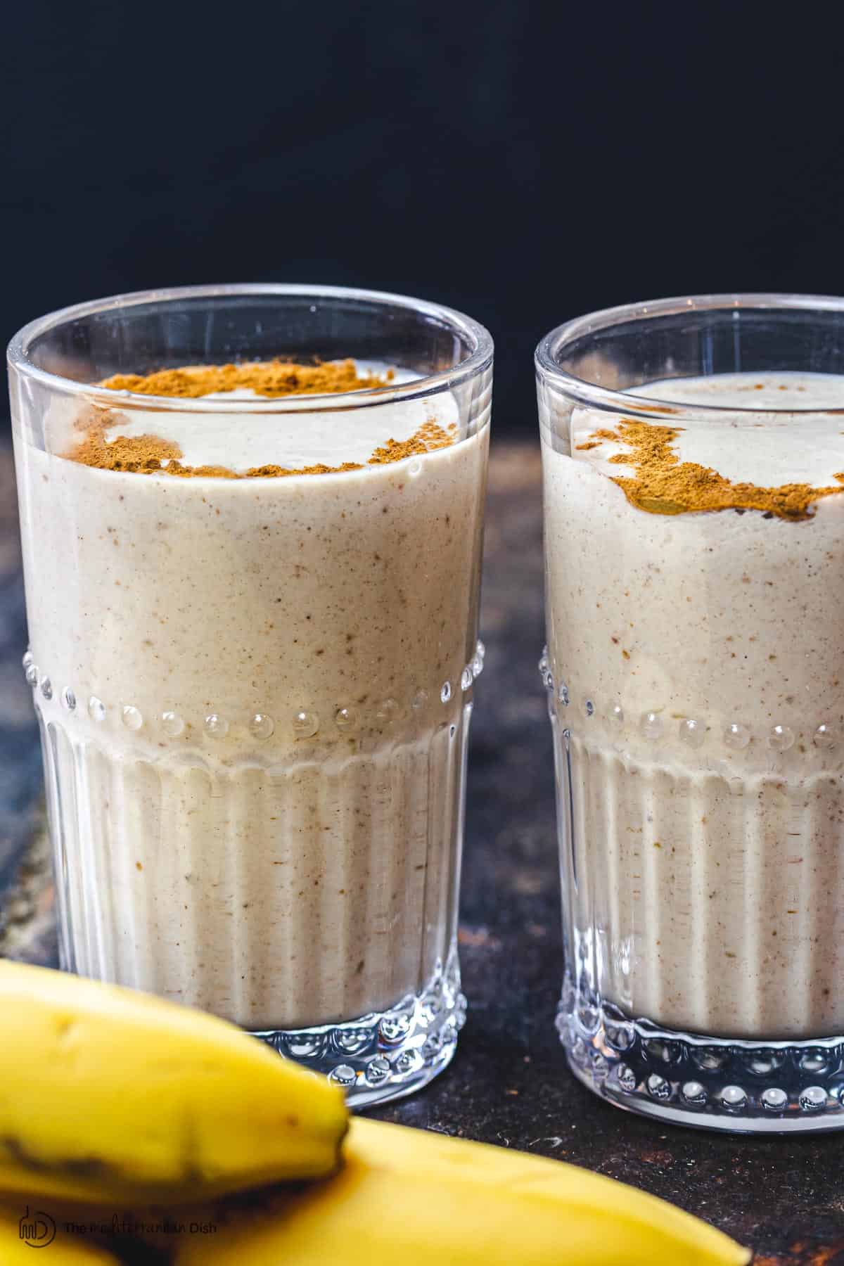 Two glasses of banana shake. Sprinkle of cinnamon at top.