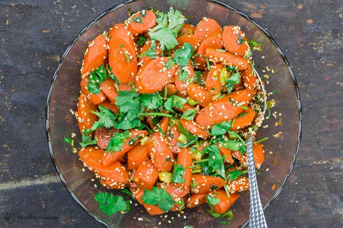 Moroccan carrot salad in mixing bowl. Sesame seeds added