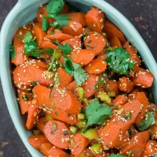 Moroccan carrot salad, garnished with fresh cilantro and toasted sesame seeds