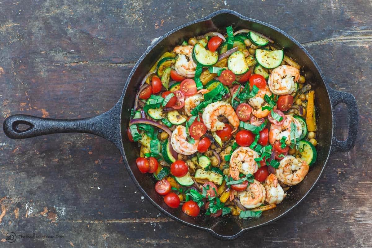 Final step of cooking sauteed shrimp and vegetables. Adding fresh lemon juice, tomatoes and basil