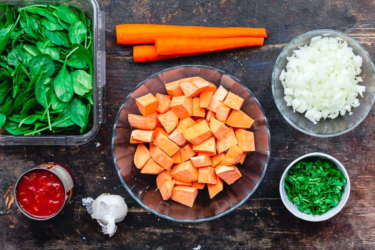 Ingredients for sweet potato stew. Sweet potatoes, spinach, onions, garlic, tomatoes, carrots and parsley