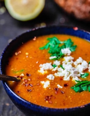 Greek red lentil soup served in a bowl with a sprinkle of feta cheese on top. Crusty bread to the side