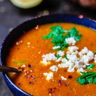 Greek red lentil soup served in a bowl with a sprinkle of feta cheese on top. Crusty bread to the side