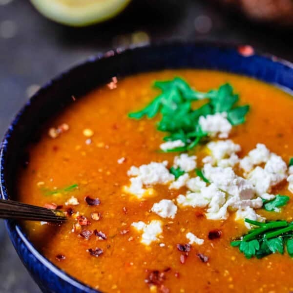 Greek red lentil soup served in a bowl with a sprinkle of feta cheese on top. Crusty bread to the side