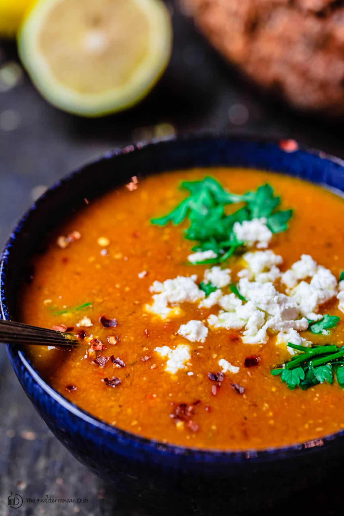 Greek red lentil soup served in a bowl with a sprinkle of feta cheese on top. Crusty bread to the side