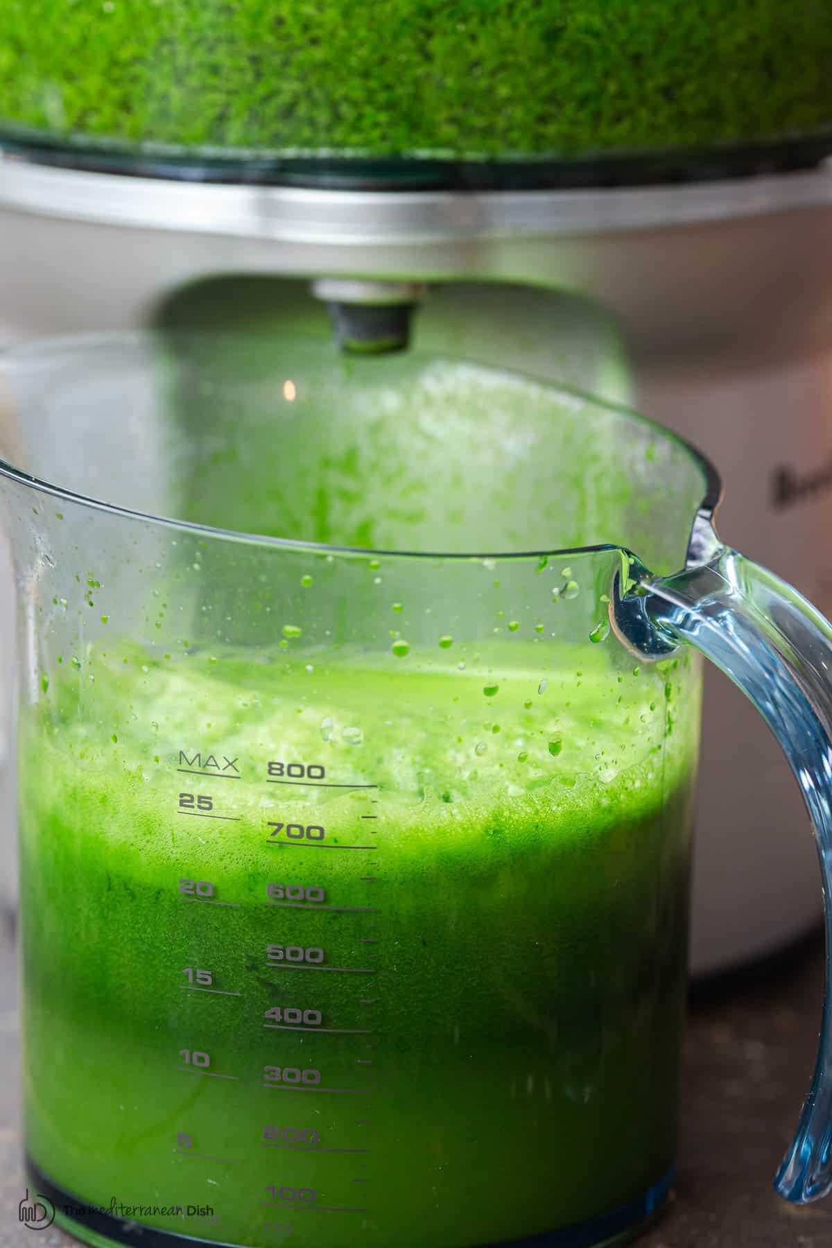 Juicer and pitcher full of green juice 