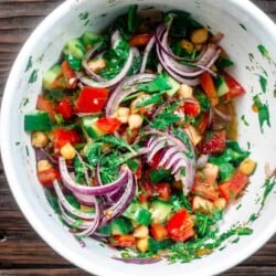 chickpea salad tossed with veggies and herbs in mixing bowl