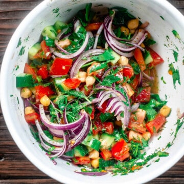 chickpea salad tossed with veggies and herbs in mixing bowl