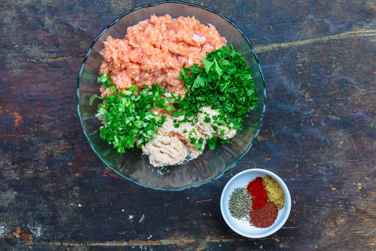 Salmon, fresh herbs, and spices in a bowl to form salmon burger mixture