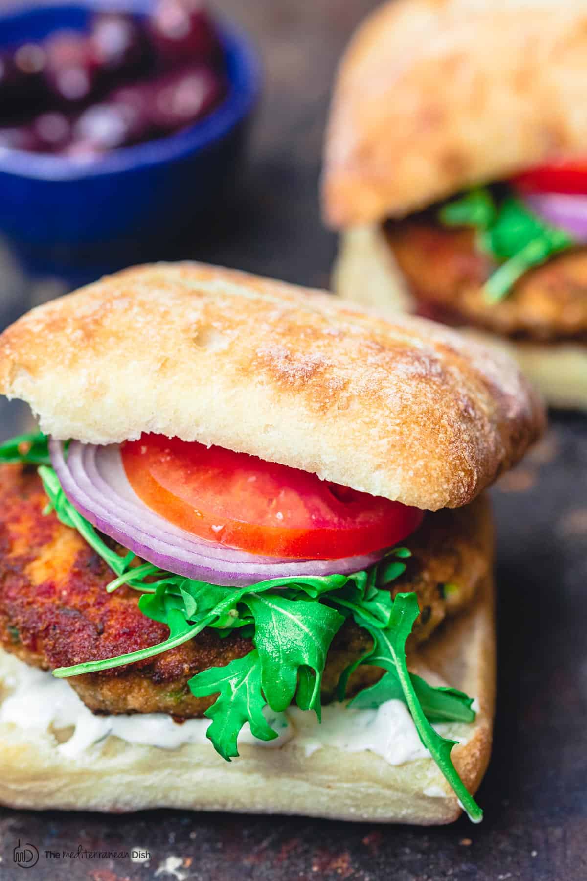 Juicy salmon burgers, served in Italian ciabatta rolls with arugula, tomatoes, and sliced onions