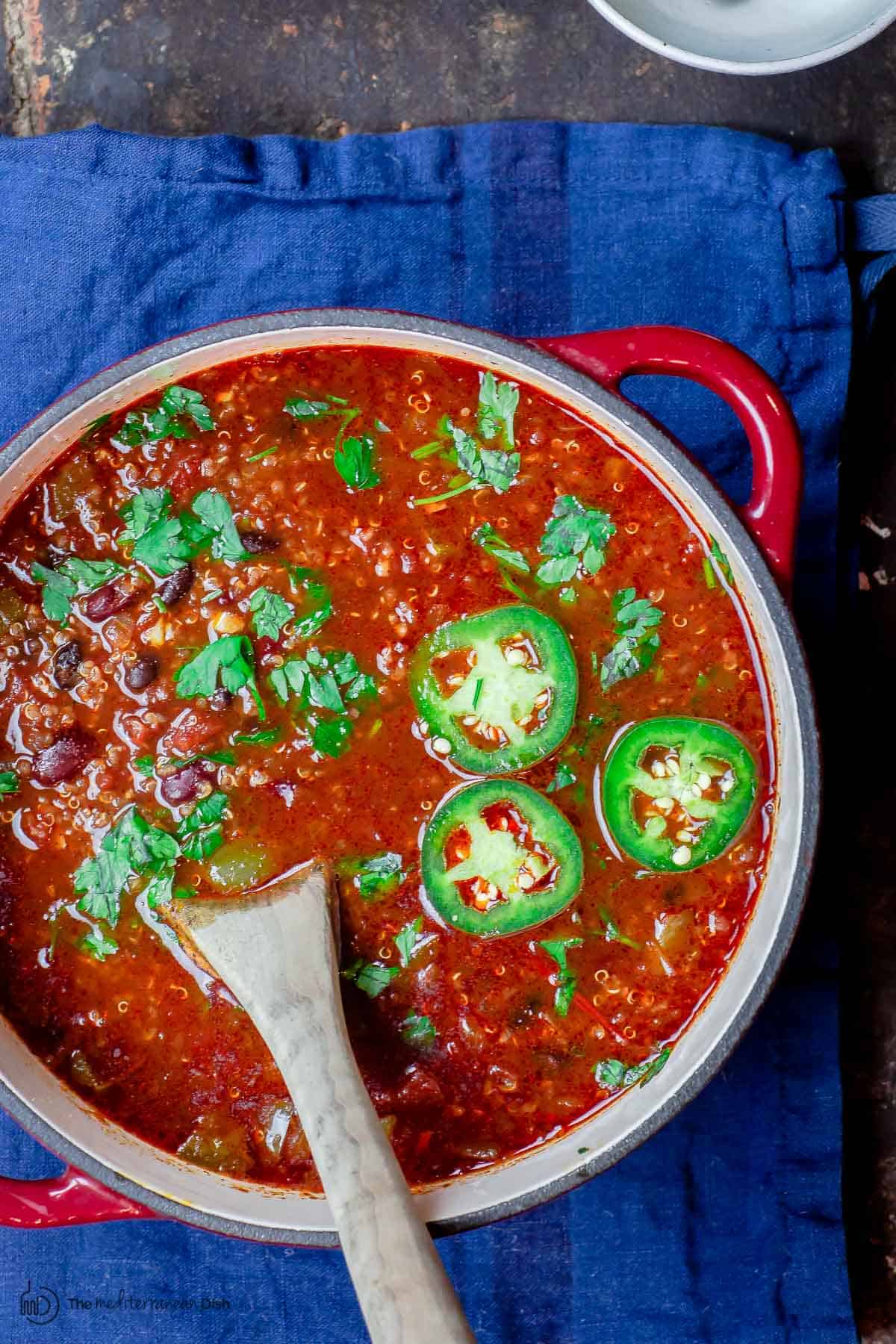 Vegan chili in a pot with quinoa and jalapenos