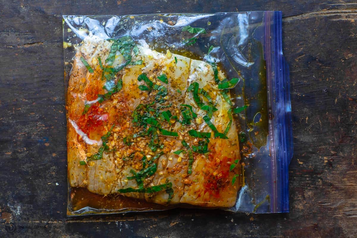 Fish fillet marinating in a large zip-top bag. Part of baked fish recipe