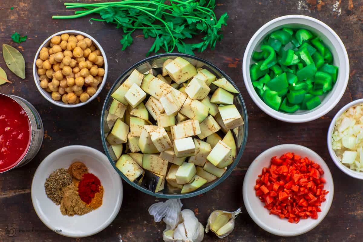 eggplant stew ingredients. Eggplant, chickpeas, canned tomatoes, carrots, onions, peppers, spices, garlic, and parsley