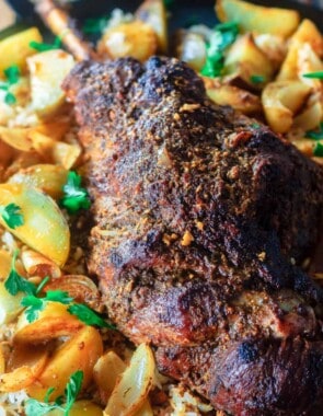 roast leg of lamb with potatoes on platter over a bed of rice