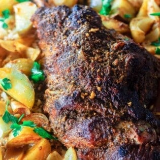 roast leg of lamb with potatoes on platter over a bed of rice