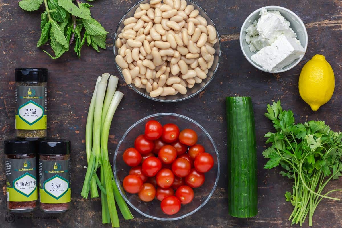 Ingredients for white bean salad. White beans, tomatoes, cucumber, green onions, herbs, spices and feta