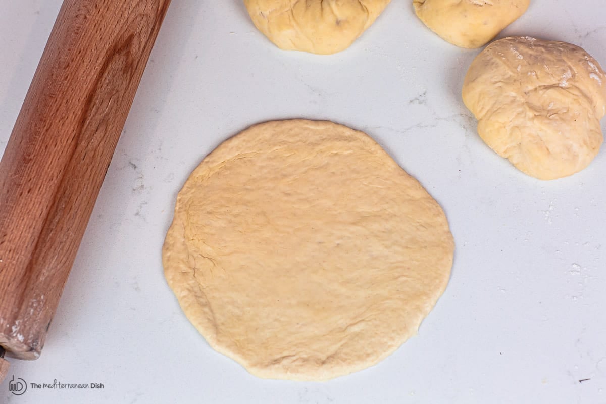 dough flattened into pita round disc 