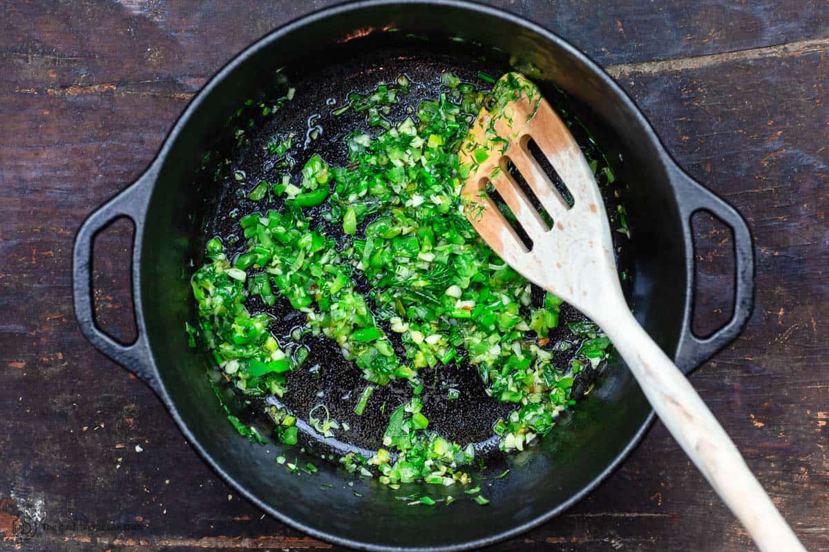 Green onions, garlic, bell peppers, and dill cooking in a pot