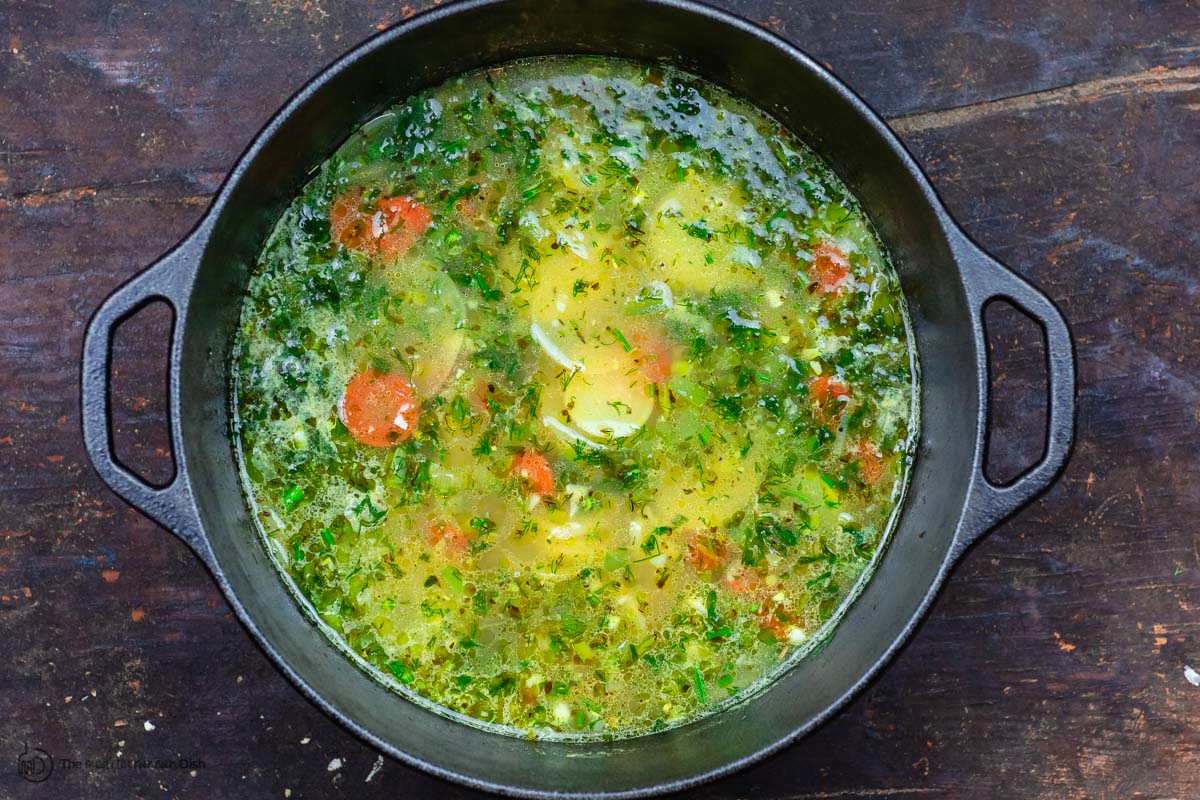 Broth, potatoes, carrots and spices are added to the pot to make the salmon soup