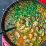 A large pot of mushroom barley soup garnished with parsley