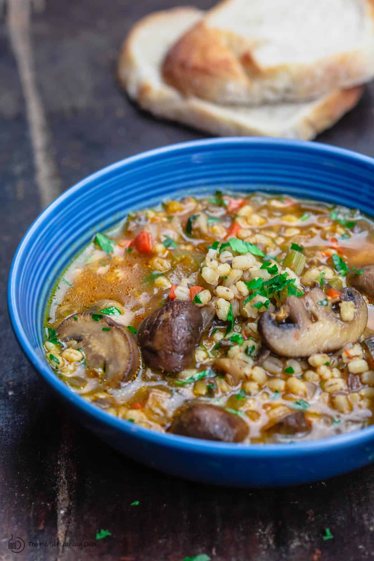 mushroom barley soup served in a bowl with a side of sliced bread