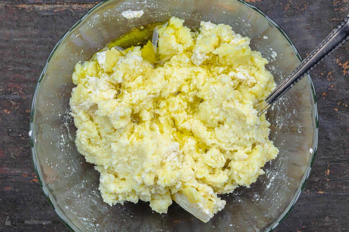 olive oil and almond paste added to the bowl of mashed potatoes and combined
