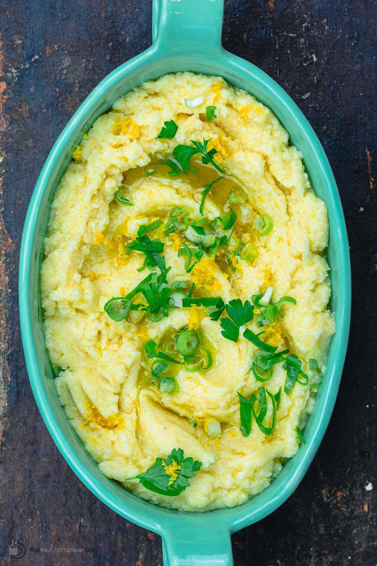 skordalia served in green bowl. Garnished with parsley and green onions and lemon zest