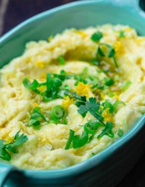 Skordalia greek garlic mashed potato dip in serving bowl with scallions and parsley for garnish