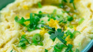 Skordalia greek garlic mashed potato dip in serving bowl with scallions and parsley for garnish