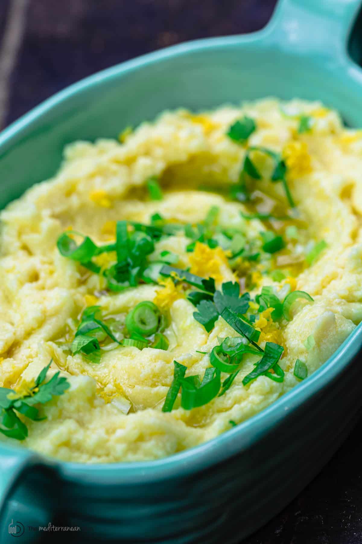 Skordalia greek garlic mashed potato dip in serving bowl with scallions and parsley for garnish