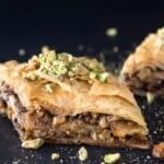 Two pieces of Greek baklava with pistachio pieces sprinkled on top