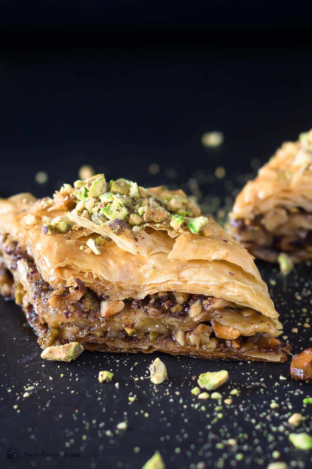 Two pieces of Greek baklava with pistachio pieces sprinkled on top