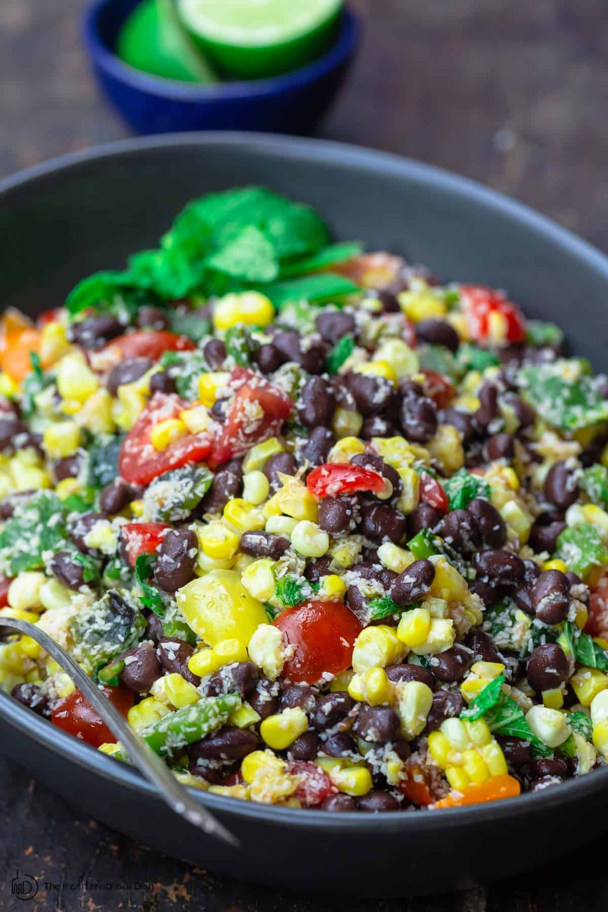 Black bean and corn salad with mint garnish. limes to the side