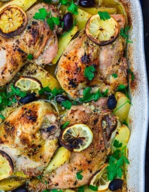 Greek chicken and potatoes garnished with parsley, olives and lemon slices