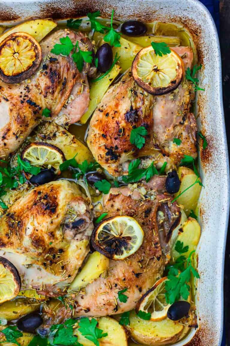 Greek chicken and potatoes garnished with parsley, olives and lemon slices
