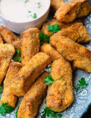 homemade fish sticks served with sauce and a sprinkle of fresh parsley
