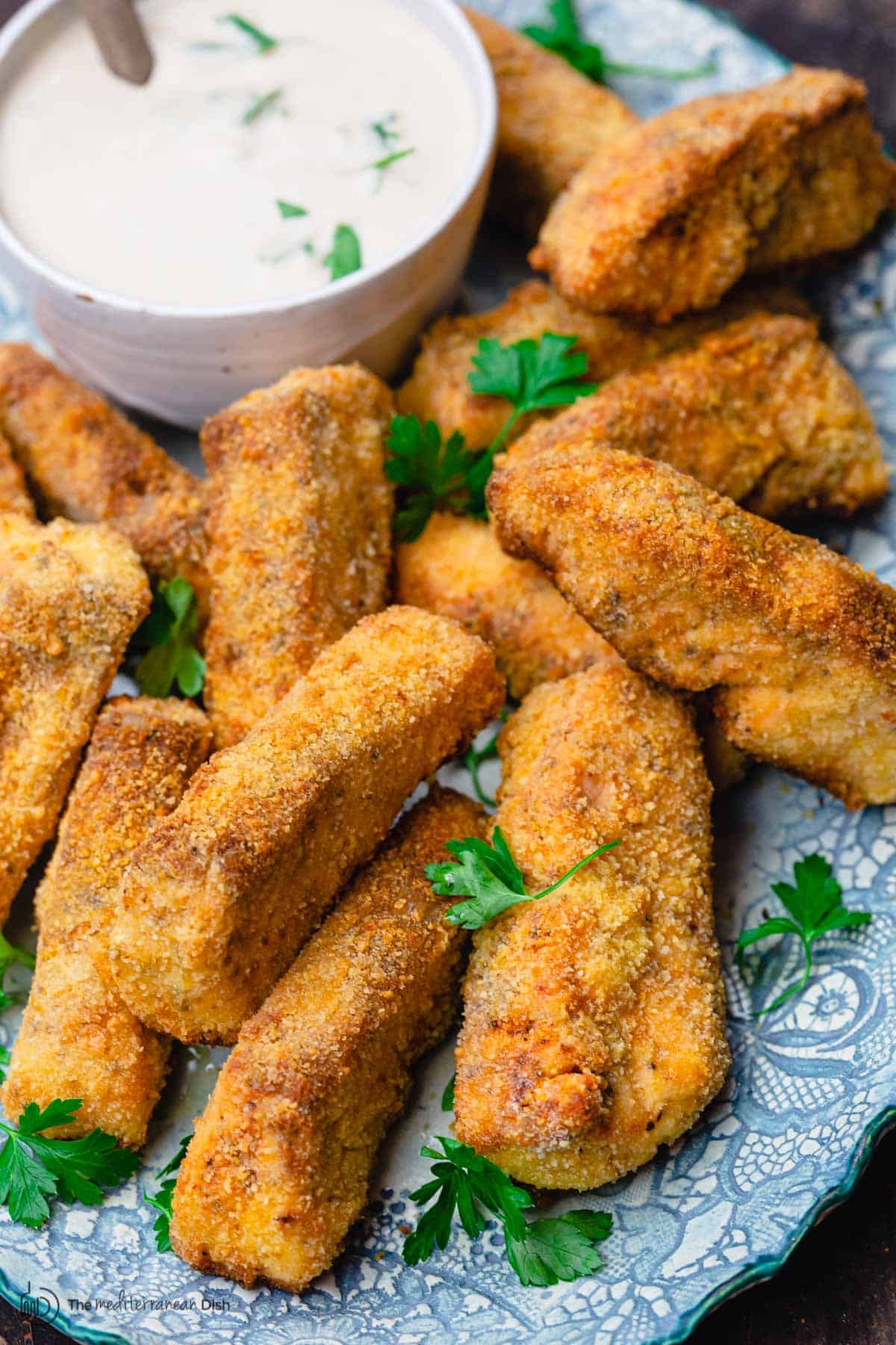 homemade fish sticks served with sauce and a sprinkle of fresh parsley