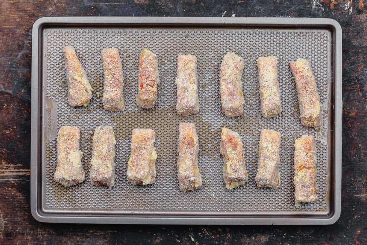 coated salmon fish sticks arranged on sheet pan for baking