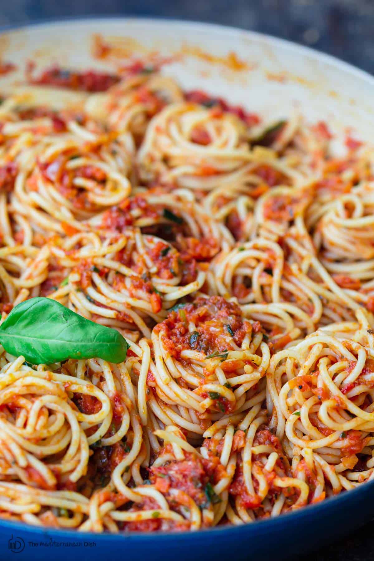 Spaghetti covered in sauce and garnished with fresh basil