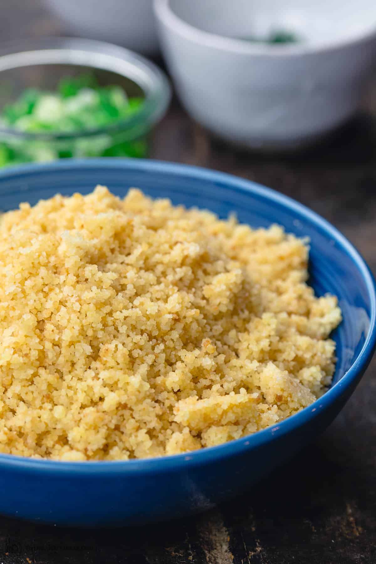 plain couscous in a bowl. herbs in different bowls to the side