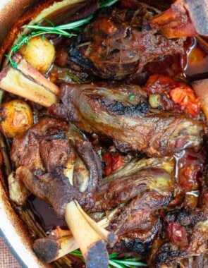 Braised lamb shanks with potatoes, carrots and rosemary in Dutch oven