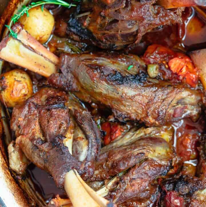 Braised lamb shanks with potatoes, carrots and rosemary in Dutch oven