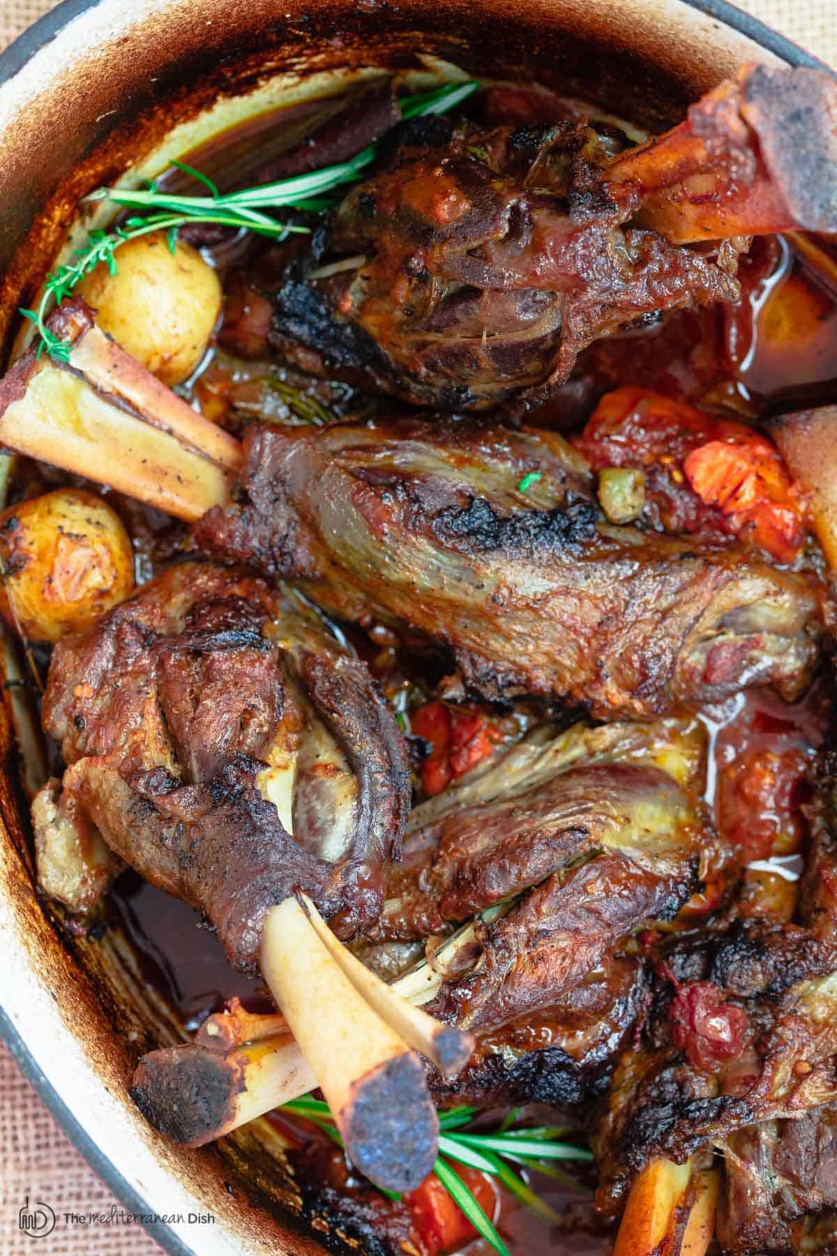 Braised lamb shanks with potatoes, carrots and rosemary in Dutch oven