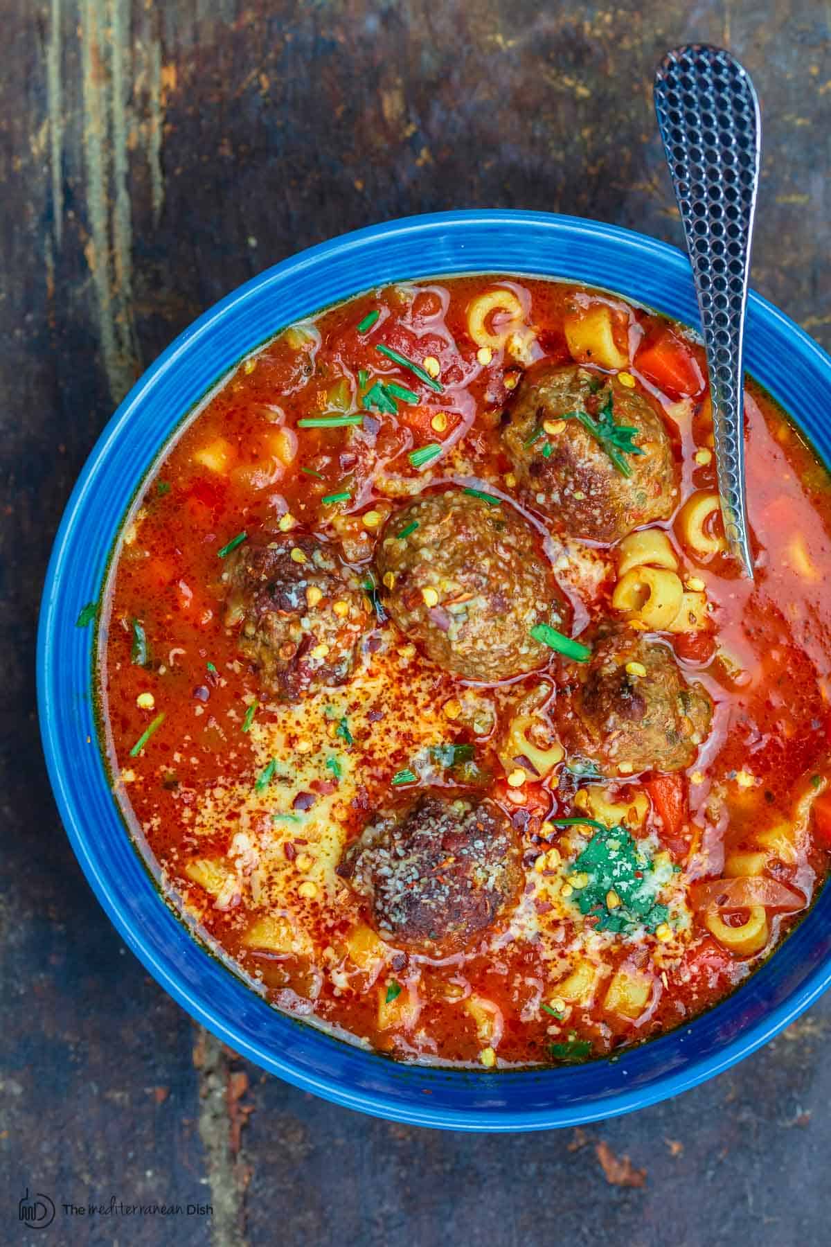meatball soup in a blue bowl with a spoon