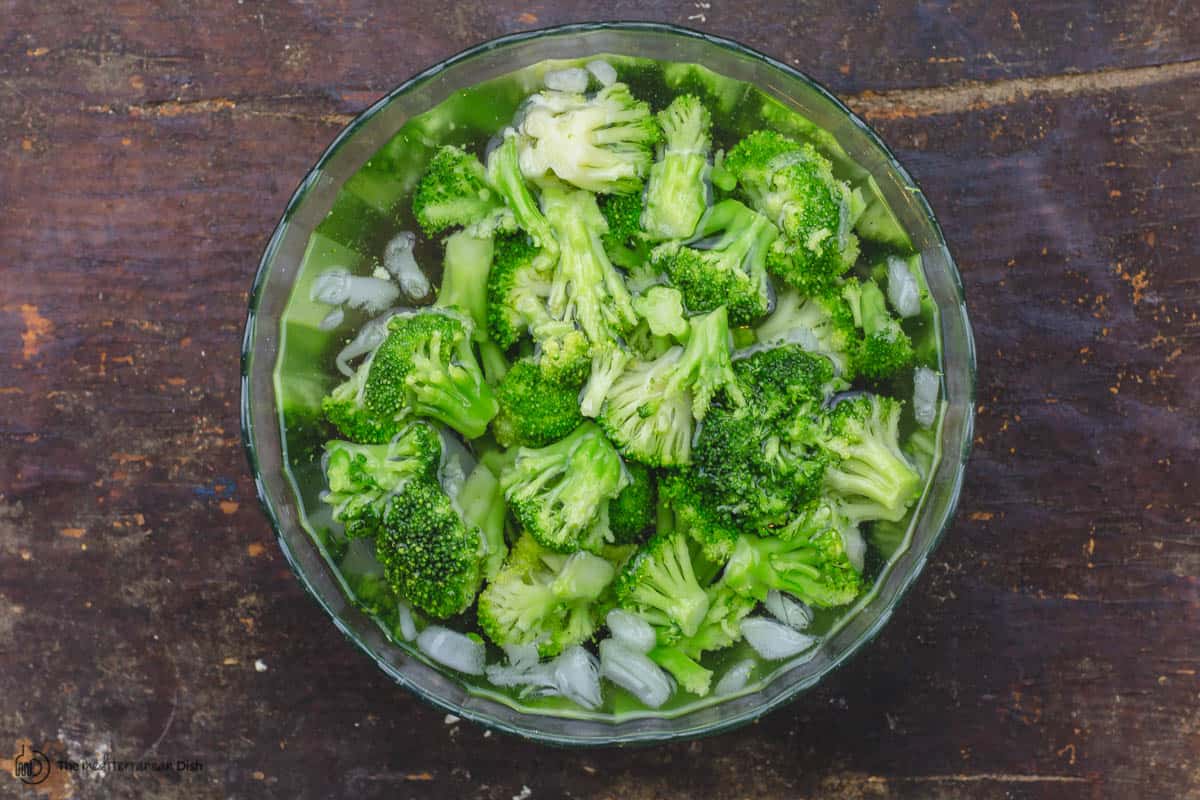 Broccoli florets in a large bowl of ice water